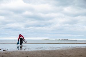 Man carries SUP into the ocean