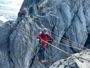 A climber on a traverse across a rock gap, made by several wires