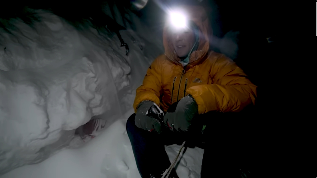 A man standing next to a tent buried in snow