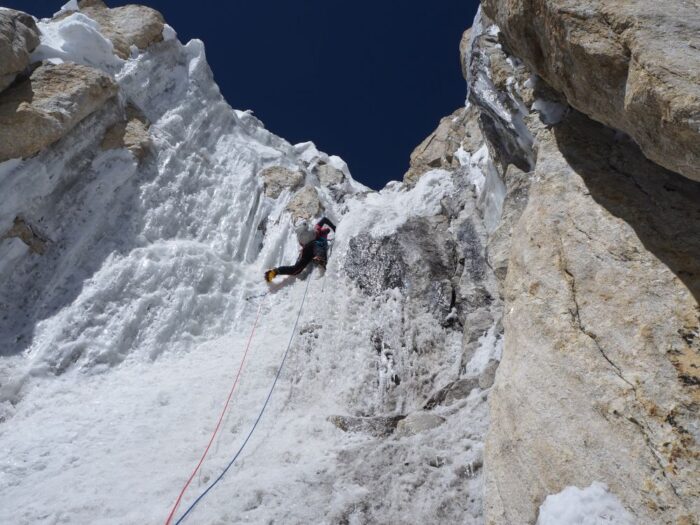 A climber on a difficult ice section leading to a ridge.