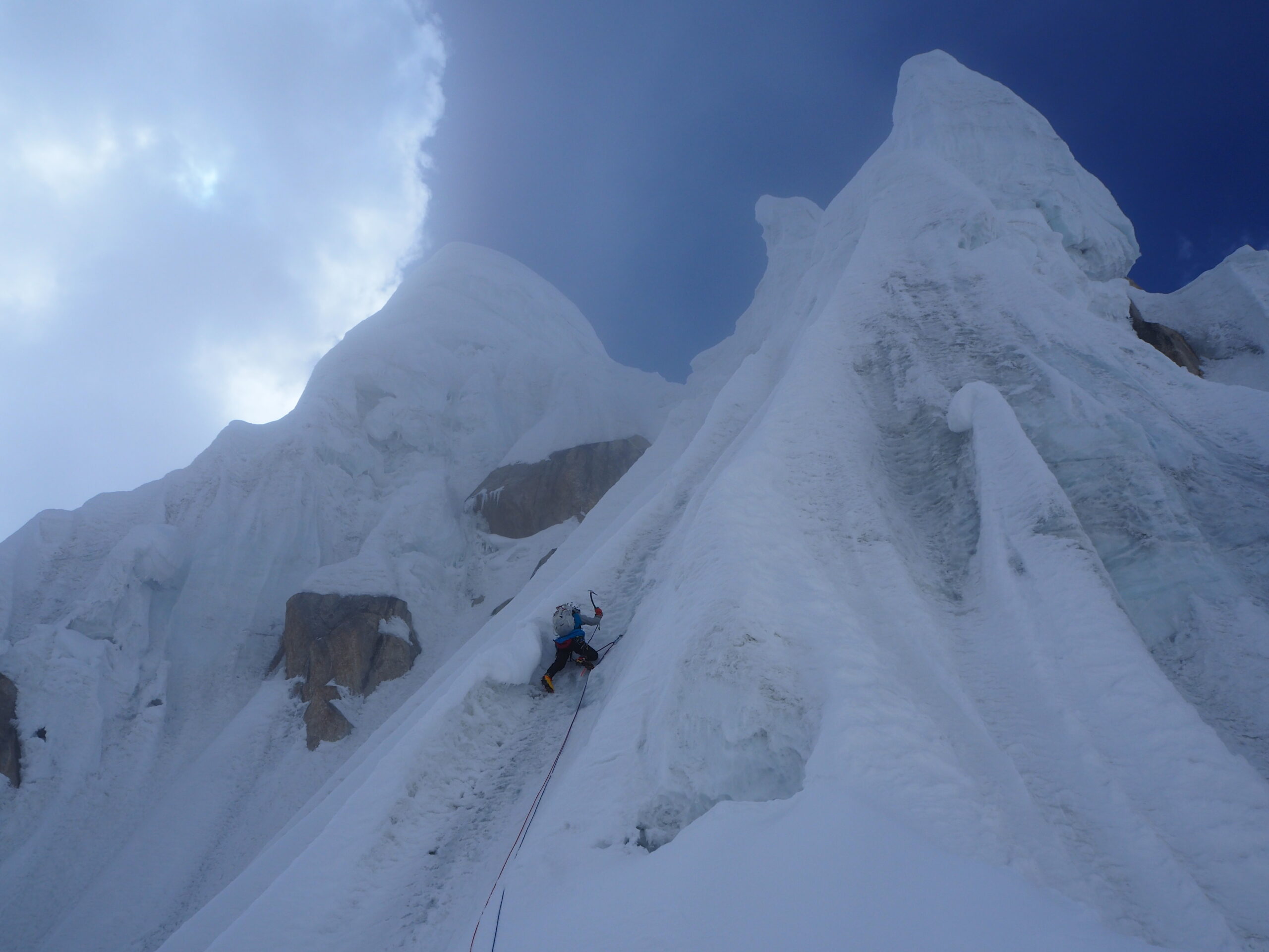 A climber on a vertical section of ice gullies leading to a summit.