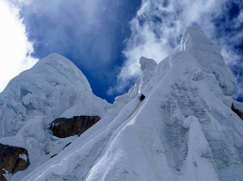 climber going up a steep ice/snow slope, seen from below