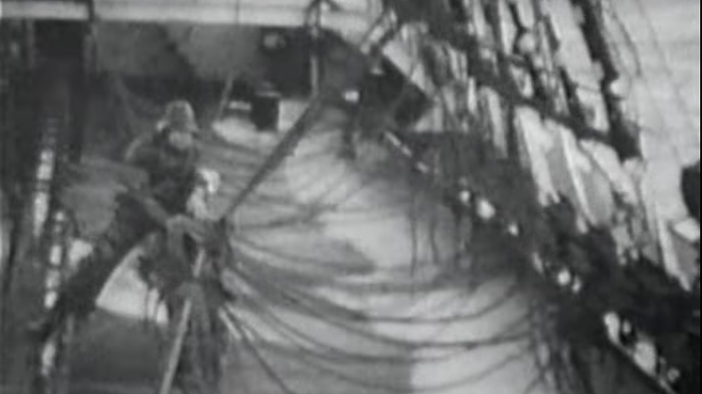 A sailor tends to the lines as seawater envelopes the Peking's deck. Still: Irving Johnson