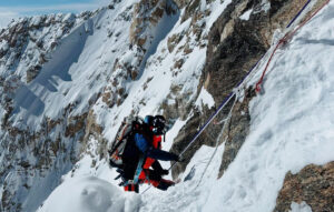 A climber approaches the summit ridge of Kangchenjunga, clipped to the fixed ropes.