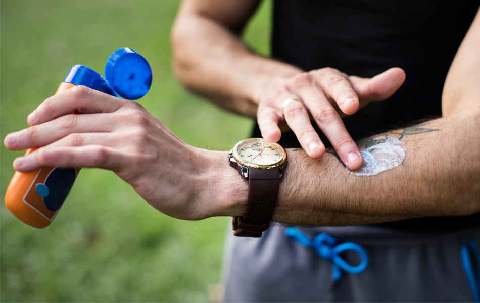man applying sunscreen on his arm