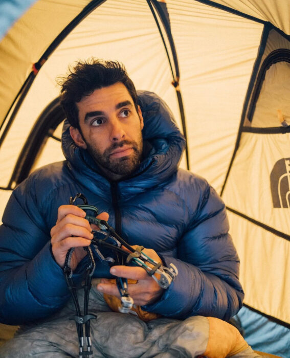 Stefano Ragazzo in a tent, fixing a piece of climbing gear. 