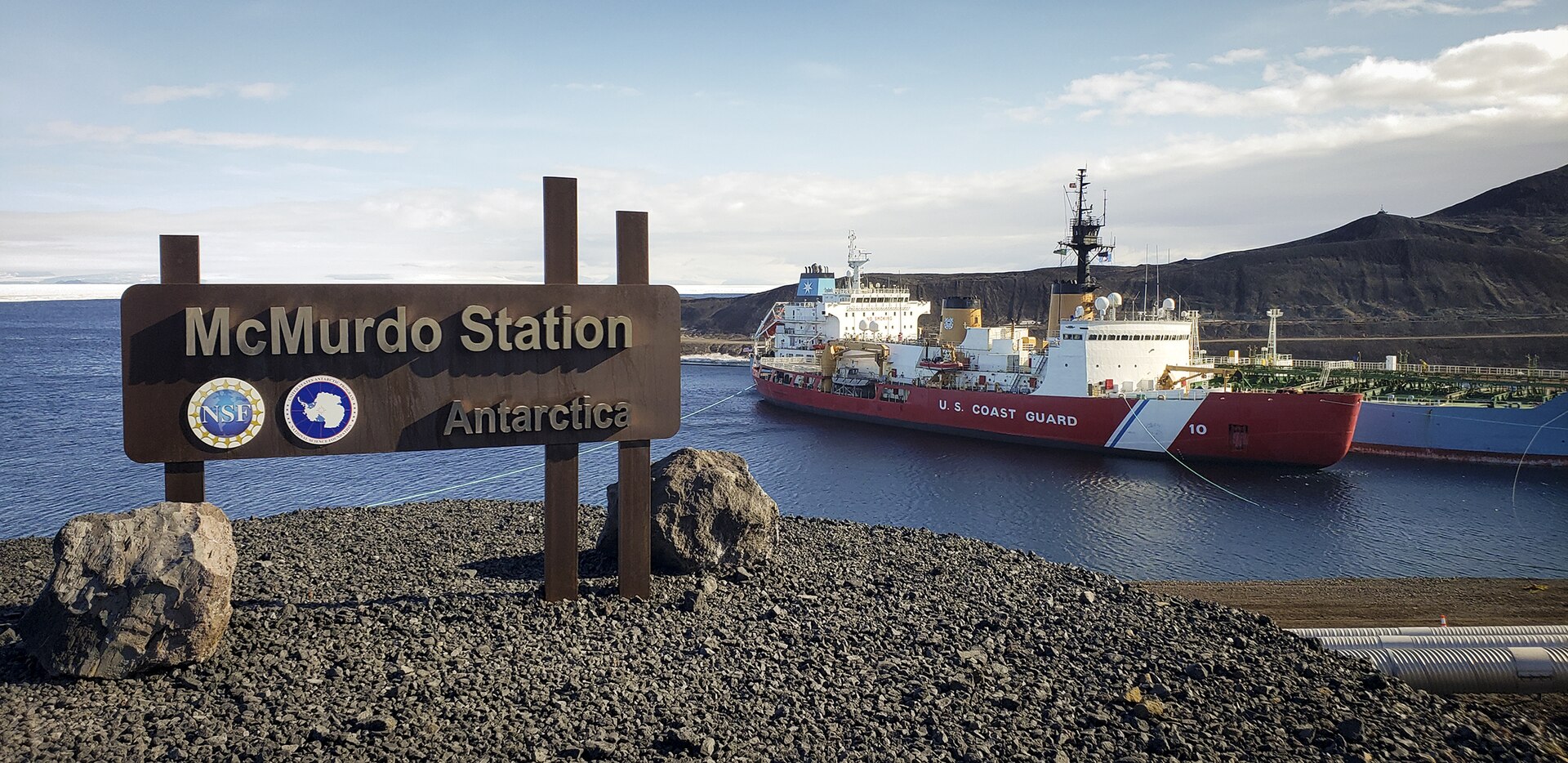 A sign reading McMurdo Station, with a ship in the background