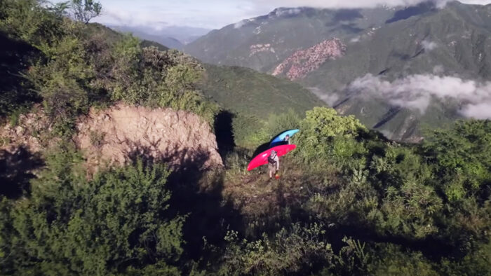 two men carry kayaks out of a canyon