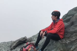 a man resting on a mountain against a gray sky