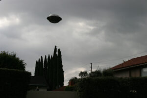 b/w illustration of flying saucer over some trees