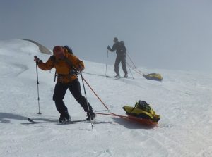 two skiers hauling sleds uphill in fog