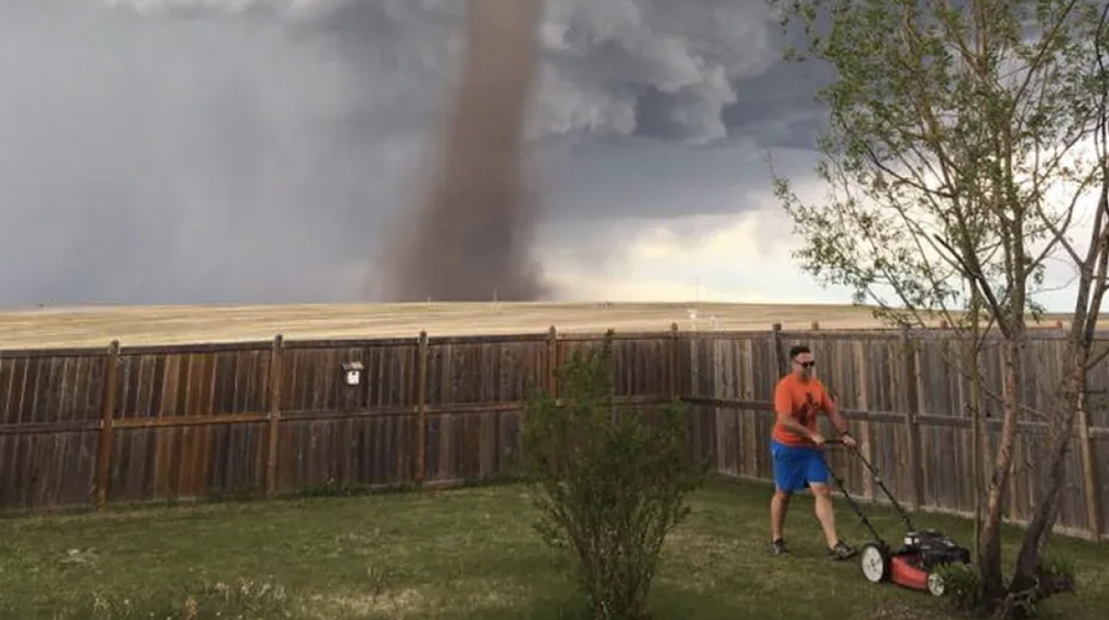 A man mows his lawn in rural Alberta, seemingly oblivious to a nearby tornado. 