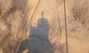 the shadow of a climber with a headcam, on a serac ice and fixed ropes.