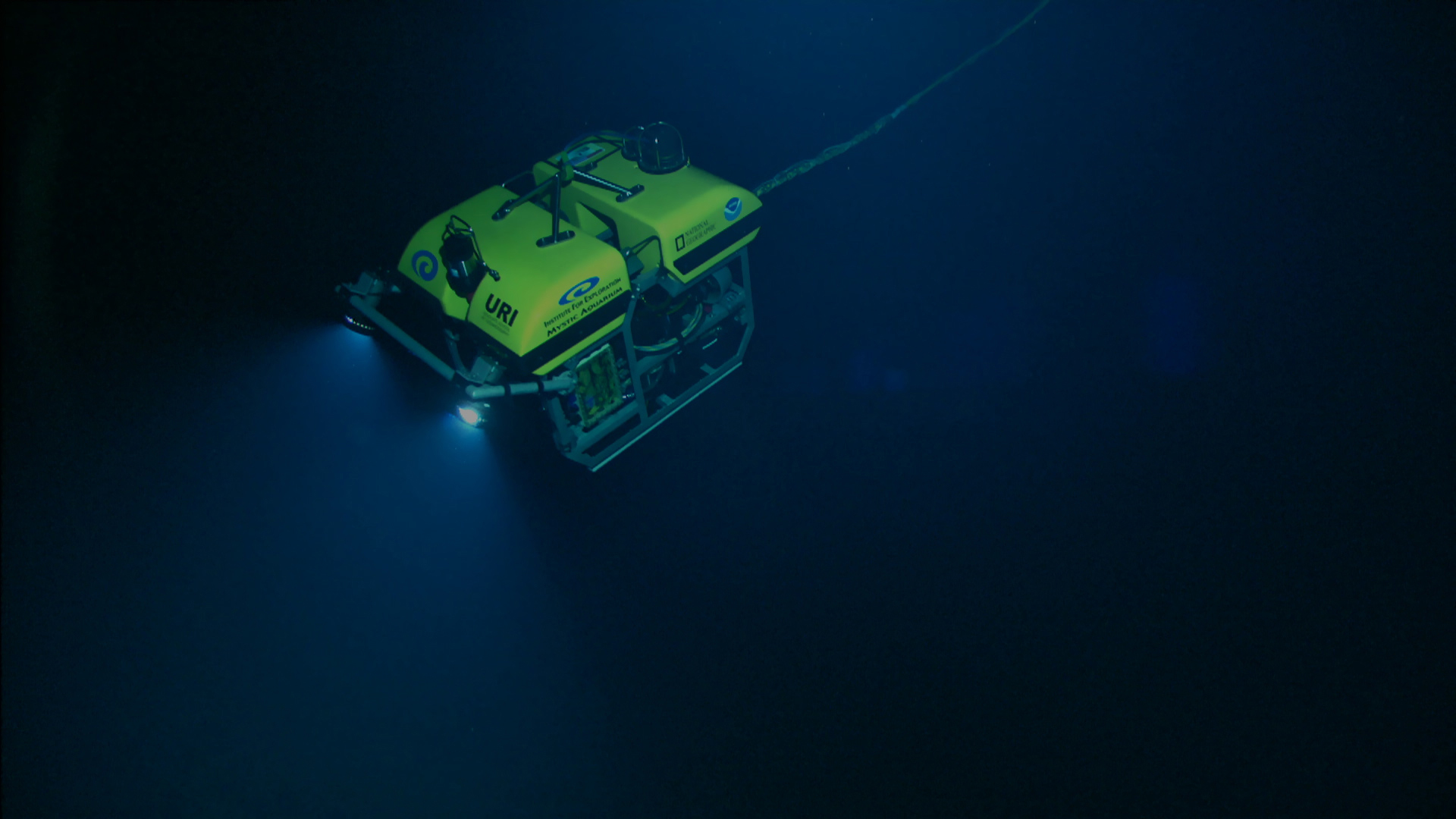 A small yellow robot with floodlights, deep underwater