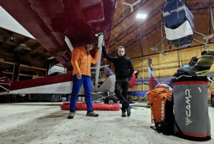 the climbers standing under the wing of a plane inside a hangar.